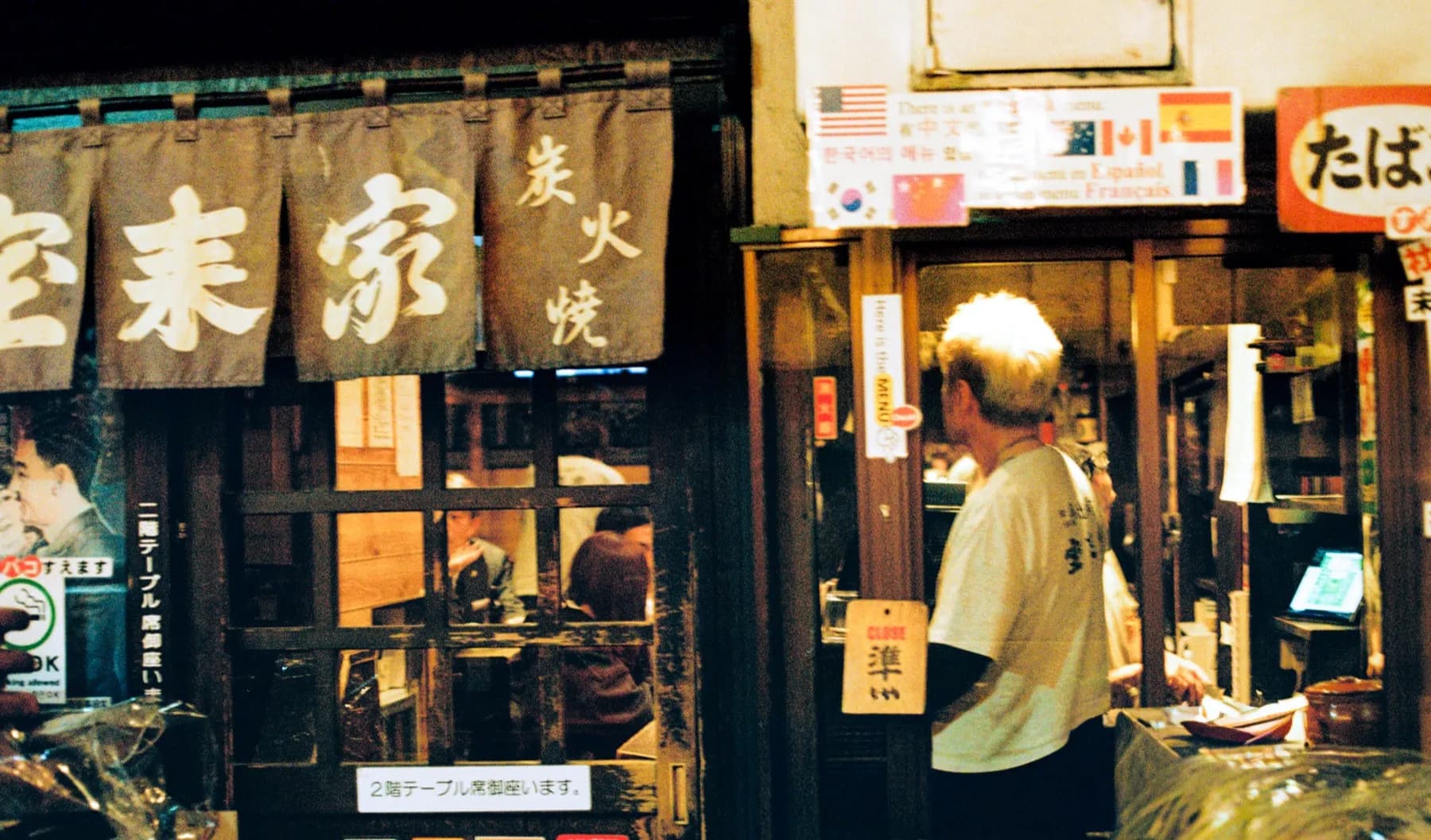 Chef working the grill behind a noren curtain at a Tokyo storefront