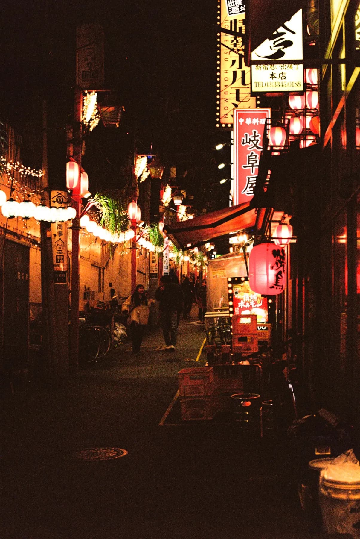 Narrow Tokyo alley strung with red lanterns at night