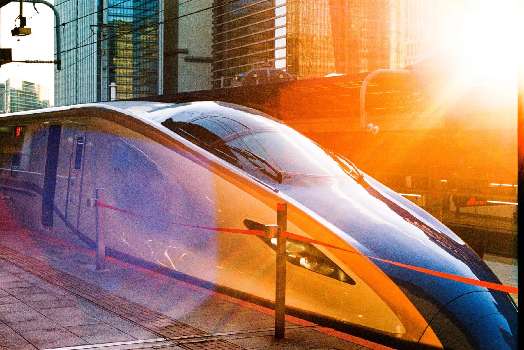 Shinkansen bullet train nose catching a sunburst on the platform