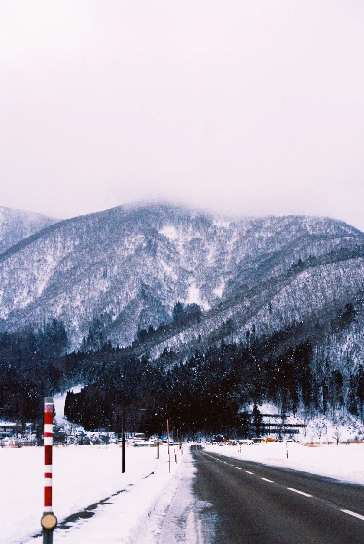 Empty road cutting toward snow-covered mountains in Japan