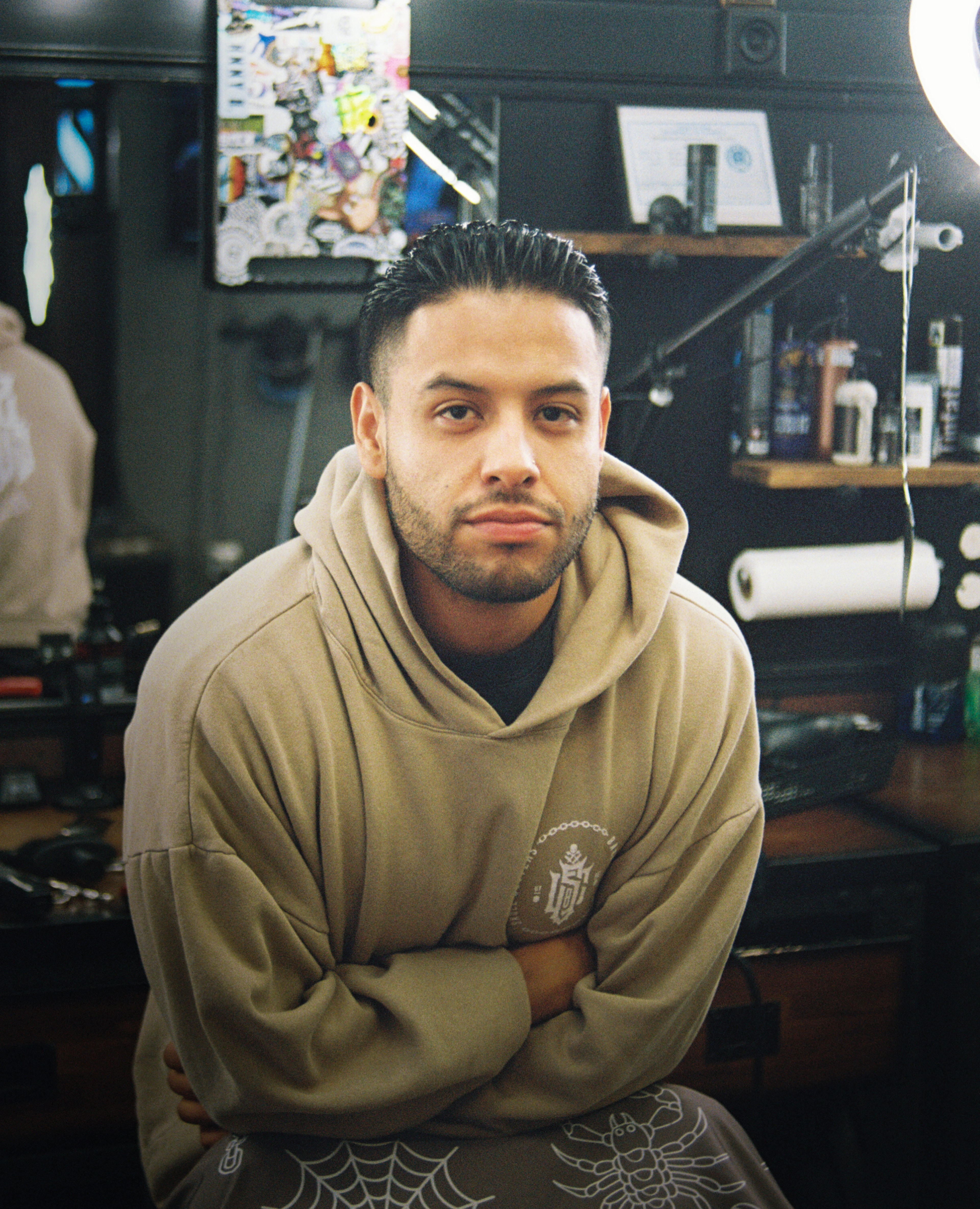 A barber sits for a portrait in his shop, shot on 35mm film in warm window light