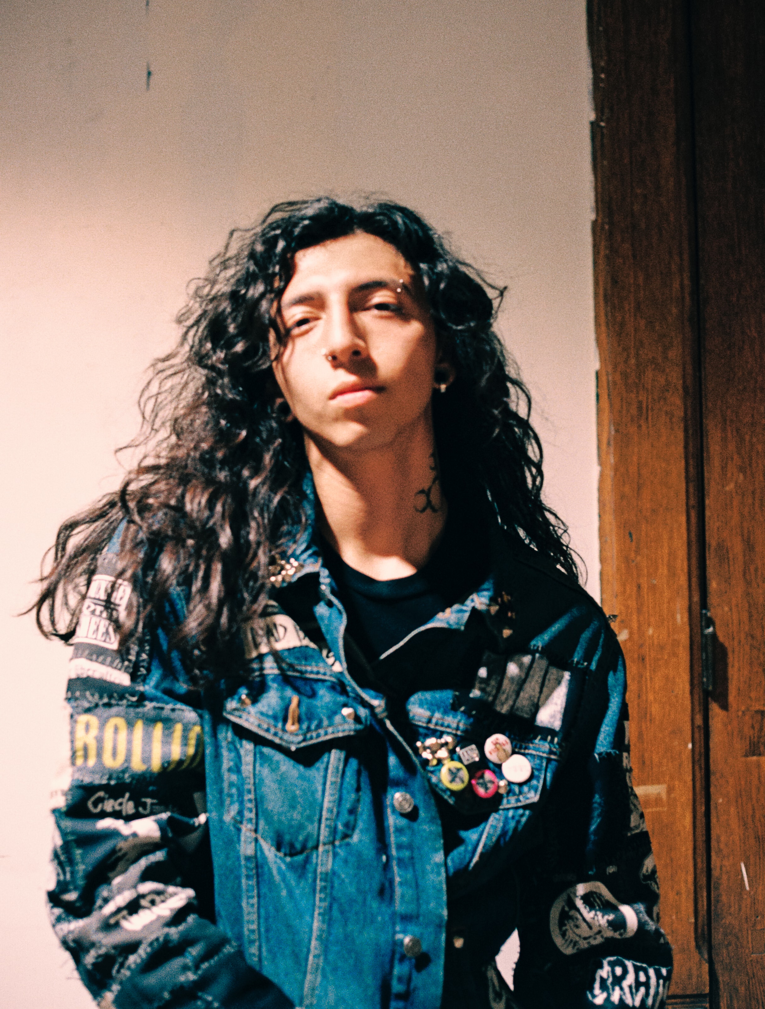 Tony in a custom jacket he patched photographed against a plaster wall on 35mm film