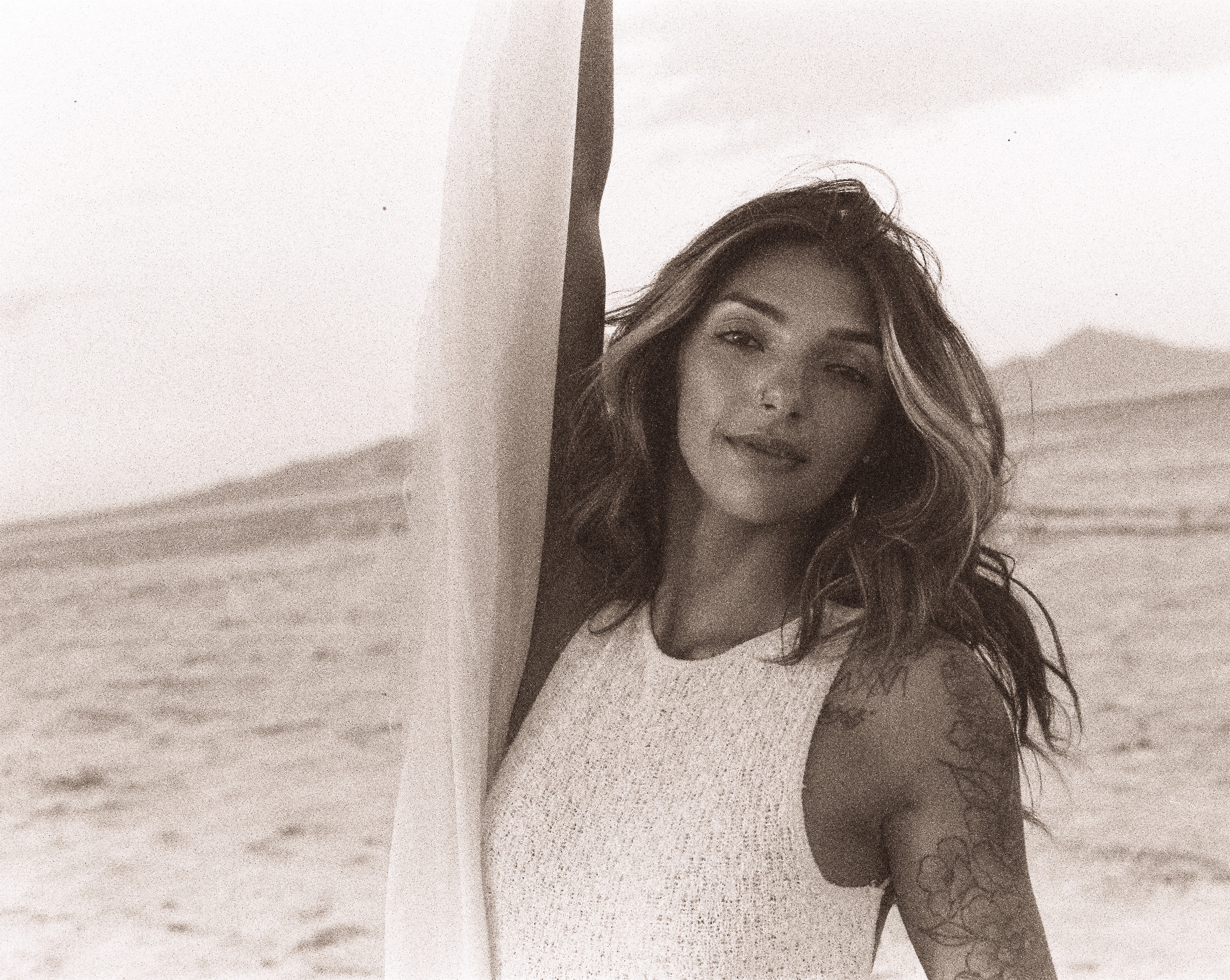 Black-and-white outdoor portrait by Salt Lake City photographer Grant Parkhurst, featuring a woman with windswept hair holding fabric beside her face in the desert.