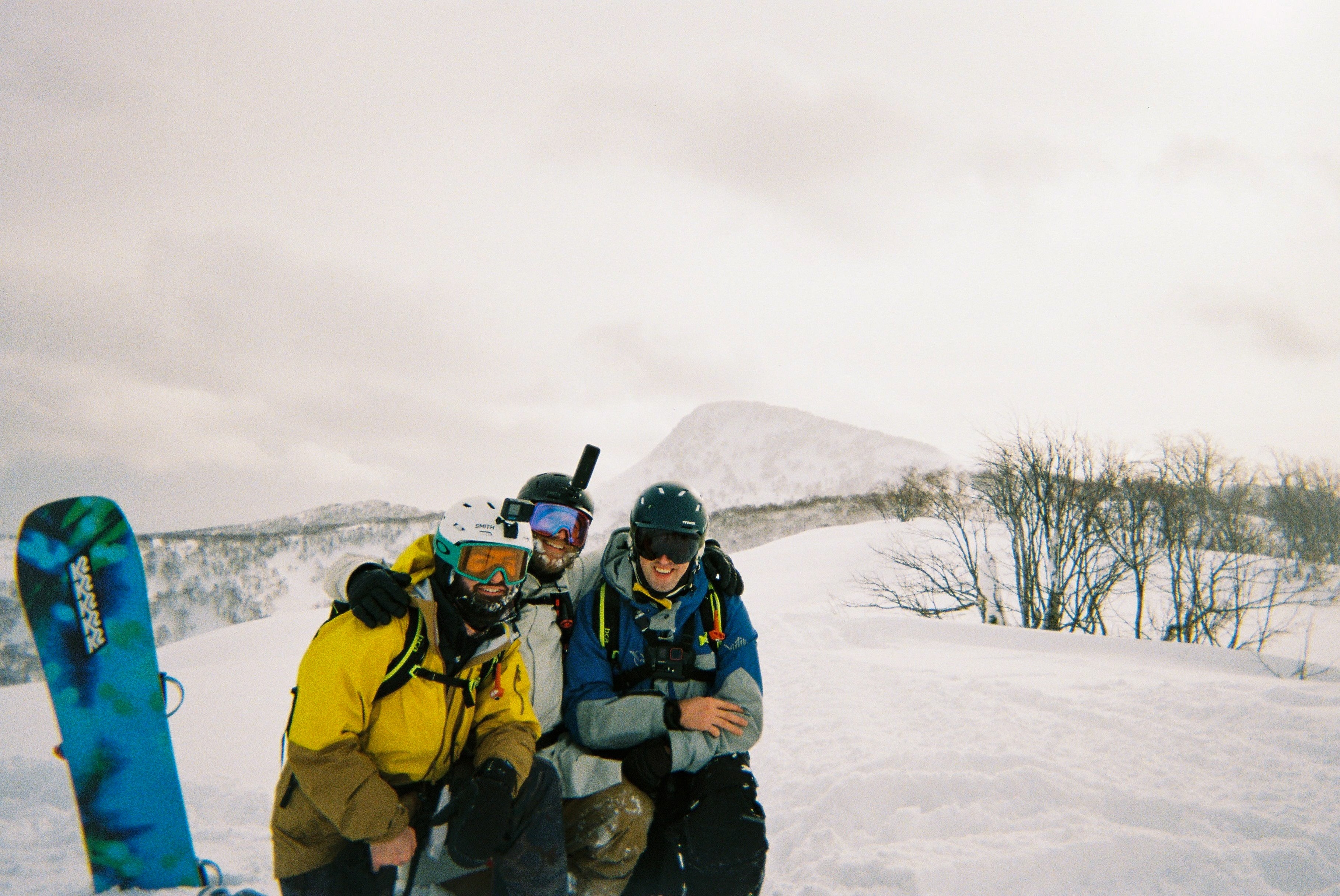 Two snowboarders resting in deep snow below Mount Yotei, shot on 35mm film