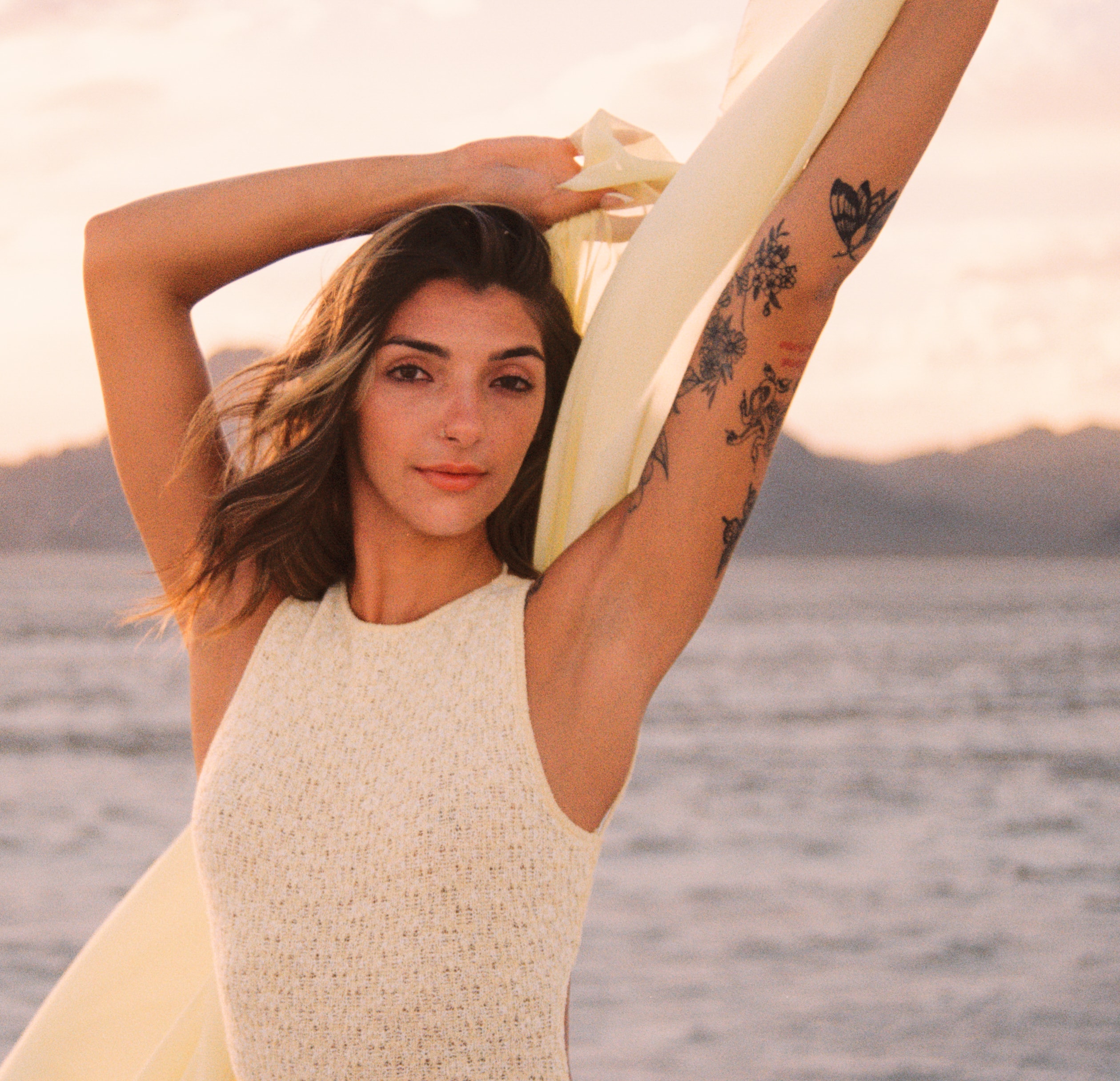 Golden-hour desert portrait by Salt Lake City photographer Grant Parkhurst, featuring a woman lifting cream fabric overhead with mountains behind her.